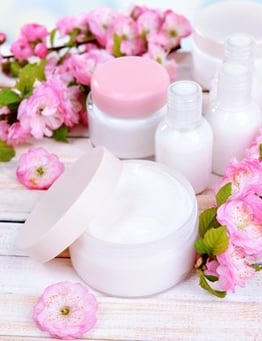kosmetyki na tle białych desek i różowych kwiatów