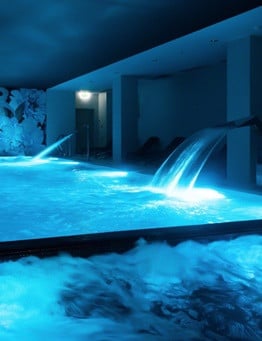 hotelowy basen z niebieskimi światłami i biczami wodnymi