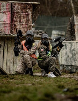 Gracze paintball chowający się za przeszkodą