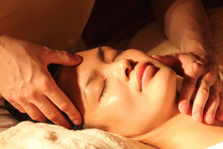 Zrelaksowana kobieta podczas masażu twarzy.