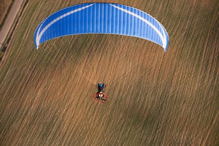 lot motoparalotnią na tle pola uprawnego