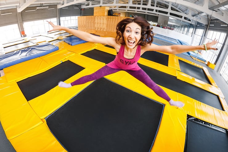 kobieta uśmiecha się do obiektywu skacząc na trampolinie