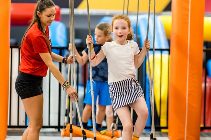 dzieci przechodzą tor przeszkód w parku trampolin