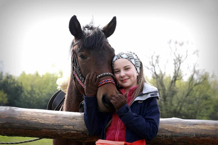 Kobieta w niebieskiej kurtce podczas jazdy konnej