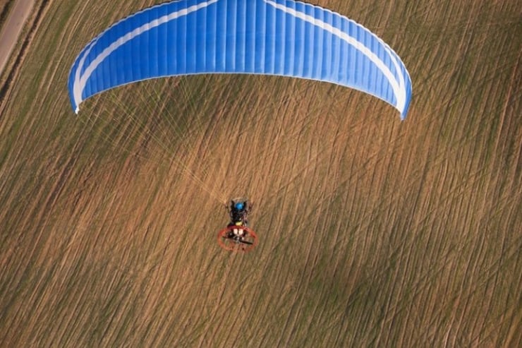 niebieskie skrzydło motoparalotni nad polem