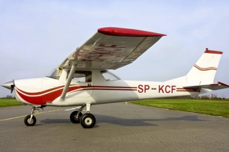 Biało-czerwona Cessna 150 stojąca na płycie lotniska